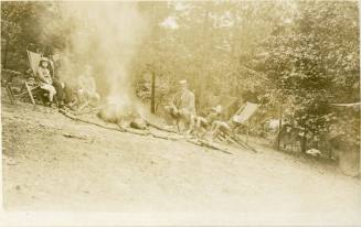 R. J. Reynolds and children sitting around campfire, circa 1915